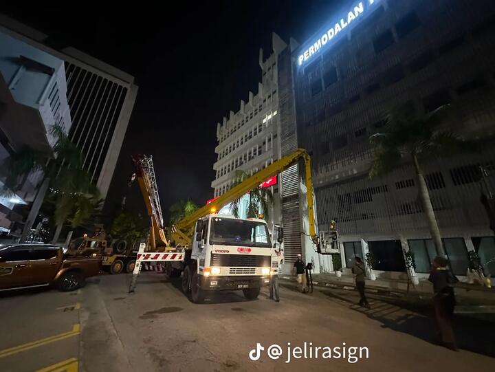 Lori skylift SOHHO memasang papan tanda bangunan pada waktu malam