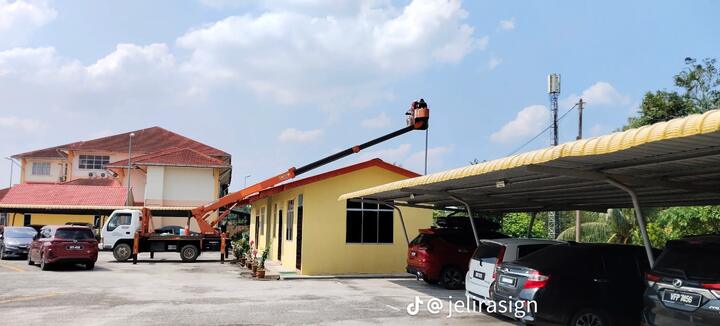 Lengan skylift oren menjangkau ke atas bumbung bangunan